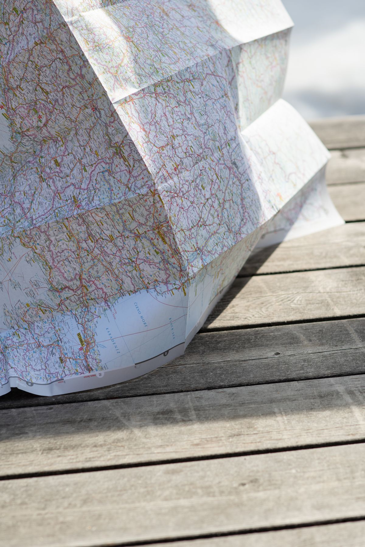 A folded paper map resting on a wooden table in sunlight.