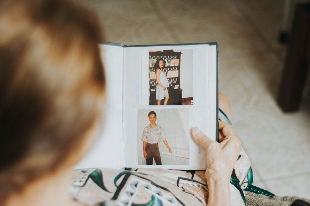 A person looking through printed family photographs in an album.